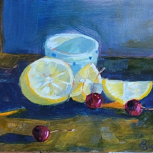 Puede incluir: Pintura al &oacute;leo de un bodeg&oacute;n con limones cortados, cerezas y una taza azul claro con un patr&oacute;n de puntos. Los limones son amarillos, las cerezas rojas, sobre un fondo azul y marr&oacute;n.