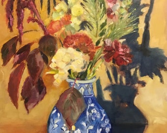 May include: A blue and white porcelain vase with a floral design holds a bouquet of flowers, including yellow, red, and white blooms. The vase is sitting on a table with a yellow background. The flowers cast a shadow on the table.