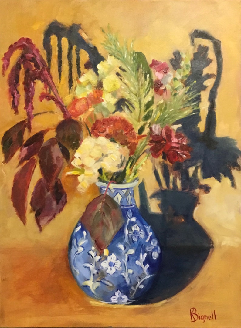 May include: A blue and white porcelain vase with a floral design holds a bouquet of flowers, including yellow, red, and white blooms. The vase is sitting on a table with a yellow background. The flowers cast a shadow on the table.
