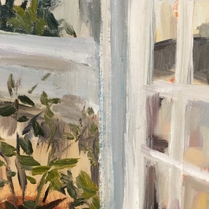 May include: A close-up of a potted plant with green leaves, partially obscured by a white window frame. The window frame has a light blue tint and is made of wood.