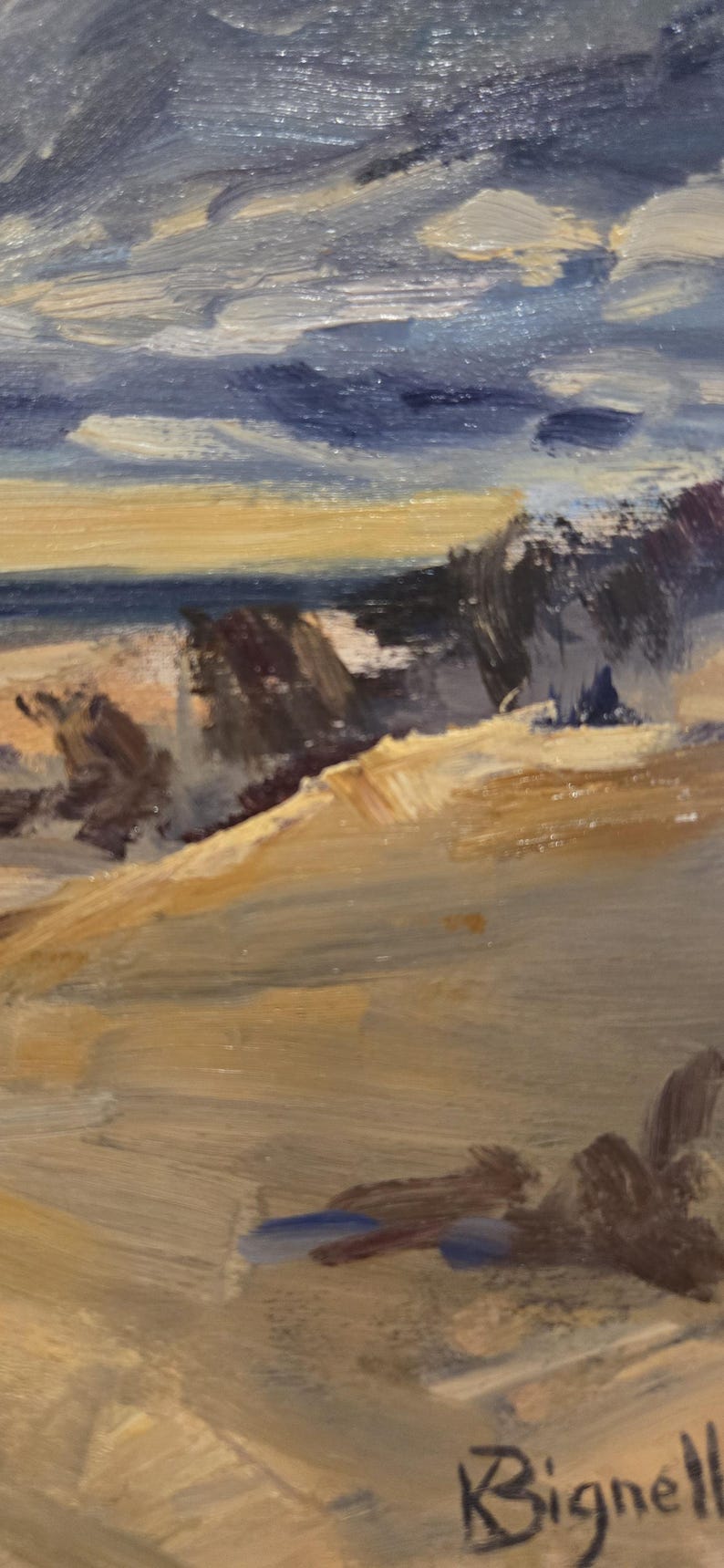 May include: An oil painting on canvas depicting a coastal landscape with a sandy beach, dark rocky formations, and a turbulent blue and grey sky. The scene features thick, visible brushstrokes in shades of tan, brown, and deep blue. The artist's signature, Bignell, is clearly visible in the bottom right corner.