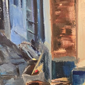 May include: Oil painting of a European street scene with blue buildings, brown barrels, and a red and pink stack of items. The artwork has visible brushstrokes and a signature in the bottom right corner.