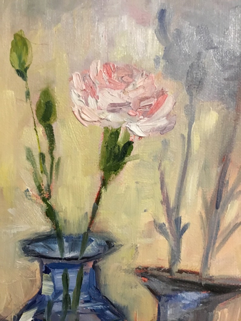 May include: Oil painting of a pink carnation flower in a blue vase. The flower is in full bloom with visible brushstrokes. Two green buds and stems are visible to the left. The background is a soft yellow with a gray shadow of a flower.