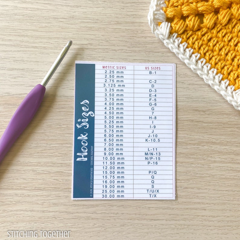 May include: A blue and white card with a chart of crochet hook sizes in millimeters and US sizes. The chart includes sizes from 2.25 mm to 30.00 mm.