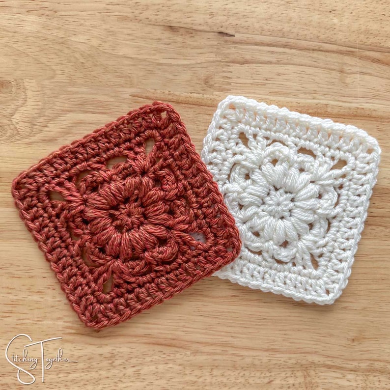 May include: Two crocheted squares, one in a burnt orange color and one in white. Both squares have a floral design in the center.