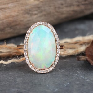 May include: A delicate oval opal ring set in rose gold with a halo of sparkling diamonds.