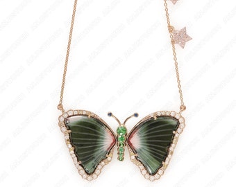 May include: A gold chain necklace with a green and pink butterfly pendant. The butterfly is made of a green stone with a pink centre and is surrounded by small diamonds. The chain has two small star charms.