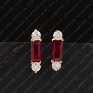 Puede incluir: Un par de pendientes de oro con piedras rectangulares rojas y piedras redondas transparentes de circonita cúbica.