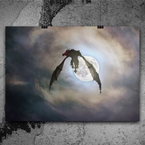 May include: A black silhouette of a dragon flying in front of a full moon in a cloudy sky.