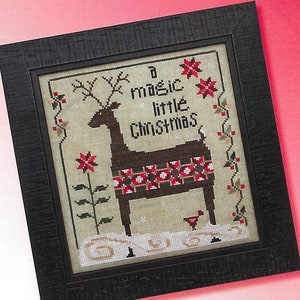 May include: A framed cross-stitch pattern featuring a brown deer with red and white patchwork on its back. The deer is standing in a snowy scene with red flowers and holly. The text "A magic little Christmas" is stitched above the deer. The pattern is titled "Patchwork Deer" and is by "Cecilia  Turner".