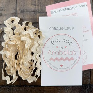May include: A bundle of beige ric rac lace next to a white card with the text "Antique Lace" and a pink card with the text "Make Finishing Fun Ideas". The cards feature the logo "Ric Rac by Anabella's".