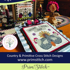 Peut inclure: Un motif de point de croix représentant une pancarte d'accueil avec le texte "Welcome to our coop" et deux poules. Le motif est encadré et exposé sur une table avec d'autres motifs de point de croix et une poupée de chiffon.