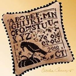 May include: A beige cross-stitch sampler with black embroidery depicting a crow perched on a pumpkin. The sampler includes the alphabet, the words "Ye old crow", the year "2018", and the state abbreviation "CT".