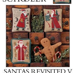 May include: The Prairie Schooler's "Santas Revisited V" book cover. The cover features four cross-stitch designs of Santa Claus, each with a unique pose and color scheme. A gingerbread man and candy canes are also visible.