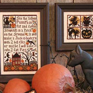 May include: A cross-stitch pattern with a black cat, a pumpkin, and a house. The text reads "See the Yellow Pumpkin fat and round Growing in a Patch on the Ground make a Jack-o-lantern with 2 big eles or maybe I will bake it into 2 fat Pies".