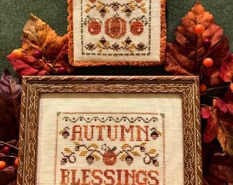 Könnte beinhalten: Zwei gerahmte Kreuzstich-Stickereien mit Herbstthema. Das obere Stück ist ein kleines Quadrat mit einem braunen Rahmen und den Worten "Grateful" und "Autumn Blessings". Das untere Stück ist ein größeres Rechteck mit einem braunen Rahmen und den Worten "Autumn Blessings".