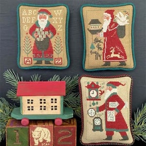 May include: Four cross-stitch patterns featuring Santa Claus in various holiday scenes. The patterns are framed and displayed on a dark gray background. The patterns include Santa with a bag of gifts, Santa with a birdhouse, Santa with a clock, and Santa with a dove.