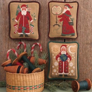 May include: Three embroidered pillow covers featuring a Santa Claus design. The first pillow cover shows Santa Claus holding a bag of gifts and standing in front of a Christmas tree. The second pillow cover shows Santa Claus holding a sign that says "Merry Christmas". The third pillow cover shows Santa Claus holding a globe and surrounded by snowflakes.