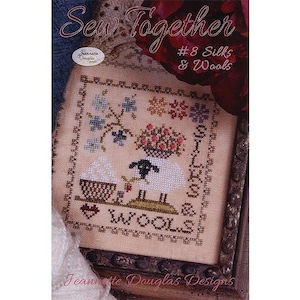 May include: A cross stitch pattern featuring a sheep with a basket of wool, flowers, and the text "Silks & Wools". The pattern is framed in a brown wooden frame.