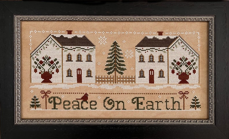 May include: Cross-stitch pattern featuring two white houses with red doors, a green evergreen tree, and red berry bushes. The text "Peace on Earth" is stitched below the houses.