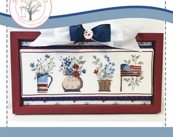 Puede incluir: Patrón de punto de cruz para un diseño floral patriótico. El patrón presenta tres jarrones con flores rojas, blancas y azules, y una pequeña bandera estadounidense. El patrón está enmarcado en un marco de madera rojo.