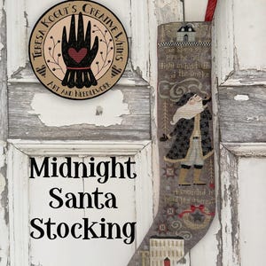 May include: A decorative Christmas stocking featuring a cross-stitch design of Santa Claus smoking a pipe, with text that reads "Midnight Santa Stocking." The stocking is gray with red accents and a red ribbon for hanging. A round sign with a hand design is also visible.
