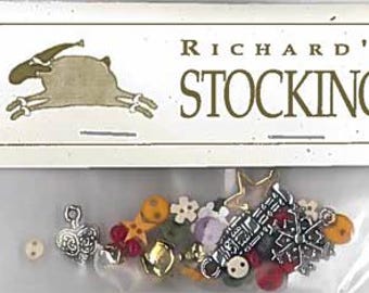 May include: A bag of assorted Christmas-themed charms and buttons, including a bell, a star, a heart, and a Christmas tree. The bag is labeled "Richard's Stocking".