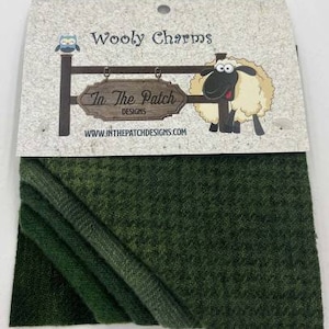 May include: Wooly Charms fabric scraps in shades of green. The fabric is textured and has a subtle ombre effect. The label reads "In The Patch Designs" and "Wooly Charms".