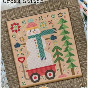May include: A framed cross-stitch design titled "The Quilted Snowman." The artwork features a snowman wearing a hat, scarf, and mittens, pulling a red wagon. The design includes snowflakes, trees, and floral elements, all in a cross-stitch style.