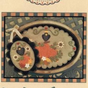 May include: A needlepoint pattern for a table mat and mini mat featuring a pumpkin with a black bird on top. The pattern is called "The Pumpkin King" and is numbered #267. The pattern is on a cream background with a brown border.