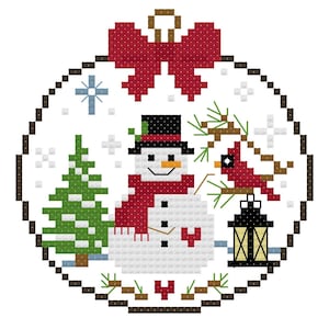 May include: A circular cross-stitch pattern featuring a snowman wearing a black top hat and red scarf, a green pine tree, a red cardinal bird on a branch, a black lantern, and a large red bow at the top, all enclosed within a brown stitched border.