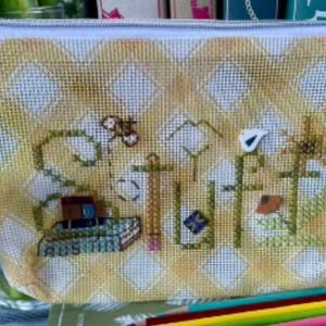 May include: A yellow and white patterned zippered pouch with the word "STUFF" embroidered on the front. The embroidery includes images of a butterfly, mountains, a bird, and a pencil. A small charm hangs from the zipper.