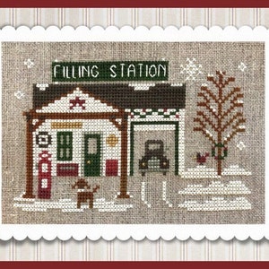 May include: A cross-stitch pattern of a winter scene with a filling station, a red car, a tree, and a dog. The sign above the station reads "Filling Station".
