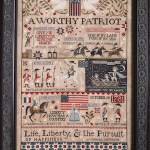 May include: A framed cross-stitch sampler with a patriotic theme. The artwork features historical scenes, dates, and text including "A Worthy Patriot" and "Life, Liberty, & the Pursuit of Happiness." The color palette includes beige, red, blue, and green.