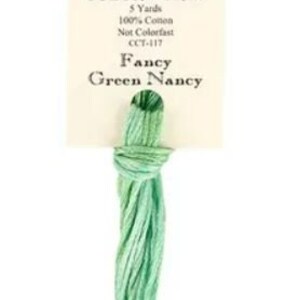 May include: A skein of green and blue embroidery floss labeled "Classic Colorworks Fancy Green Nancy" with the details "5 Yards, 100% Cotton, Not Colorfast, CCT-417".