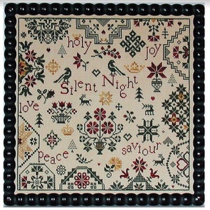 May include: A framed cross-stitch sampler with a cream background and a black beaded frame. The sampler features Christmas-themed motifs, including birds, flowers, and the words "Silent Night" and "Joy". The color palette includes red, green, and gold.
