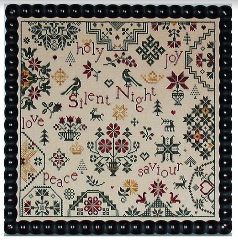 May include: A framed cross-stitch sampler with a cream background and a black beaded frame. The sampler features Christmas-themed motifs, including birds, flowers, and the words "Silent Night" and "Joy". The color palette includes red, green, and gold.
