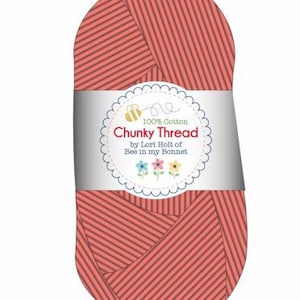 May include: A skein of coral pink chunky cotton yarn with a white label that reads "100% Cotton Chunky Thread by Lori Holt of Bee in my Bonnet."