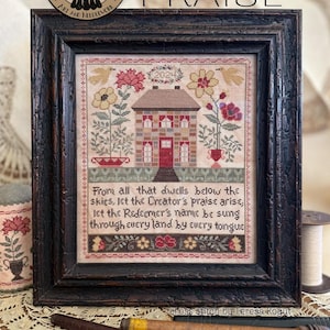 May include: A framed cross-stitch sampler featuring a house, flowers, and birds, with the text: From all that dwells below the skies, let the Creator's praise arise, let the Redeemer's name be sung through every land by every tongue. Dated 2024.