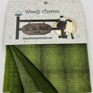 May include: A set of three green wool fabric squares with a subtle ombre effect. The fabric is labeled "Wooly Charms" and "In The Patch Designs".