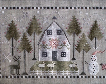May include: A cross-stitch pattern of a white barn with a red flower design on the front, surrounded by green trees and a snowman. There are also two deer and four sheep in the scene.