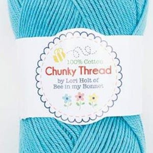 May include: A ball of turquoise chunky cotton thread with a white label. The label reads "Chunky Thread" and "100% Cotton" with a bee and flower design. The yarn is tightly wound and ready for crafting projects.