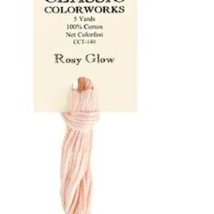 May include: A skein of pale pink embroidery floss labeled "Classic Colorworks" with the color name "Rosy Glow" and the information "5 Yards, 100% Cotton, Net Colorfast, CCT-140."