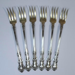 May include: Set of six silver-plated forks with ornate handles. The forks have a traditional design with a decorative floral pattern.