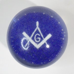 May include: A blue glass ball with a white Masonic symbol, a square and compass with a 'G' in the center.