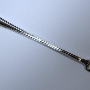 May include: A silver-plated cocktail fork with a decorative handle and three tines.