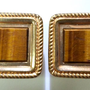 May include: A pair of gold cufflinks with square tiger's eye stones.