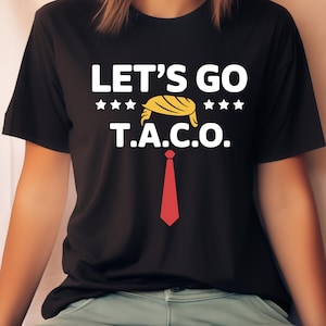 May include: Black t-shirt with the text "LET'S GO T.A.C.O." in white, featuring a yellow hair design and a red tie graphic. The shirt has three white stars above and below the hair design.