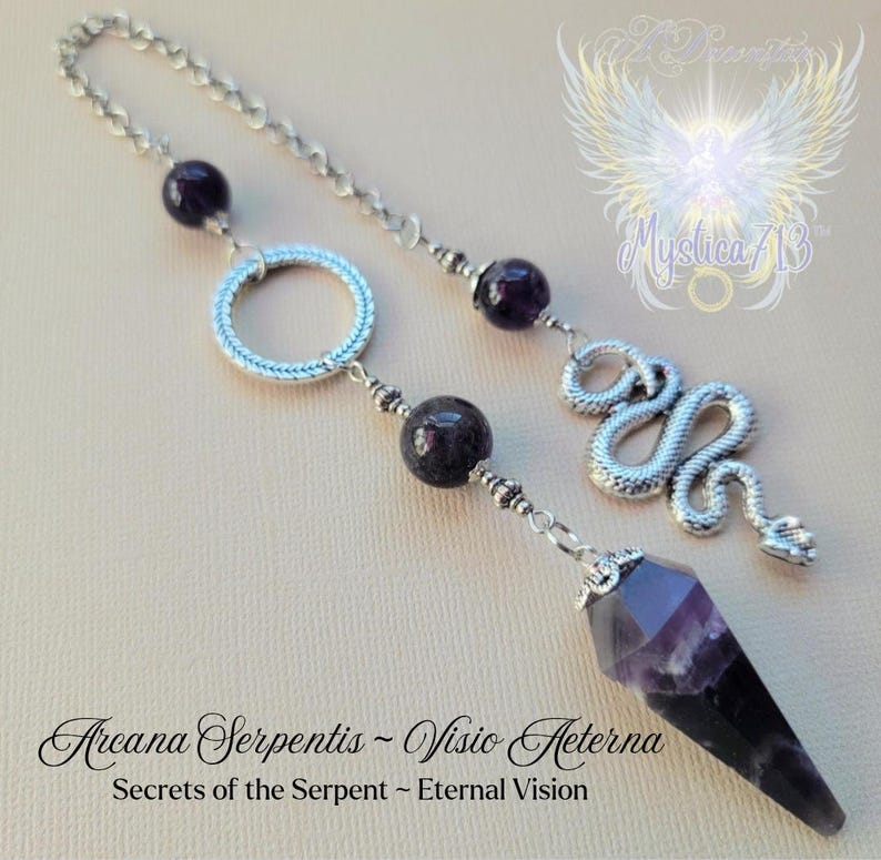 Puede incluir: Un p&eacute;ndulo plateado con una punta de cristal de amatista facetada, cuentas moradas oscuras y un dije de serpiente enroscada. El p&eacute;ndulo est&aacute; suspendido de una cadena y presenta el texto "Arcana Serpentis - Visio Aeterna".