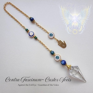 May include: A gold chain adorned with blue and green beads, and eye-shaped charms in white and blue. A clear crystal point pendant is suspended from the chain. Text reads "Contra Fascinum-Custos Vocis" and "Against the Evil Eye ~Guardian of the Voice".
